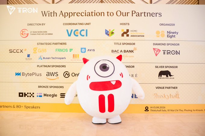 A white cyclops-like mascot stands in front of a 'With Appreciation to Our Partners' banner from TRON, listing sponsors including BytePlus, AWS, BAC A BANK, and others for an event held on 14-15.08.2026 at Thinksyhall Sala.