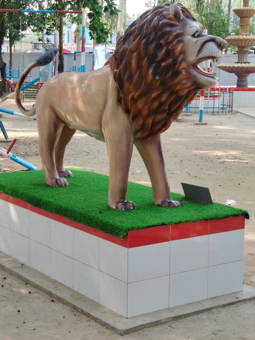 The image features a large statue of a lion standing on top of a white pedestal with red trim. The lion appears to be roaring, adding an element of intensity to the scene. The pedestal has a plaque on it that reads "Good Morning X Family... Checking out @NomismaNetwork today. Interesting progress so far. Also following @quipnetwork , @TheARCTERMINAL & @useTria What'S everyone building today?".