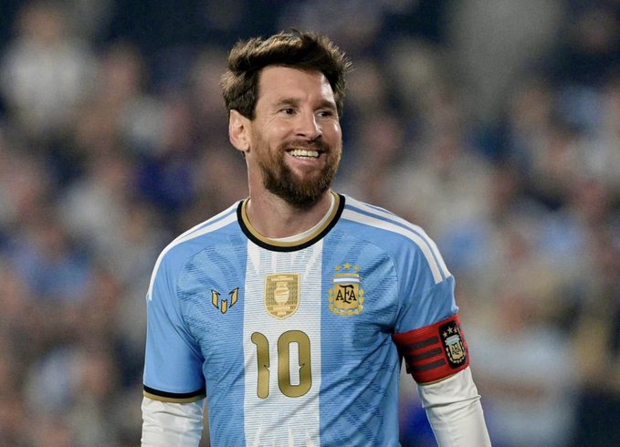 Lionel Messi smiling while wearing the Argentina national team jersey with the number 10 and AFA crest, sporting a captain's armband during a match.