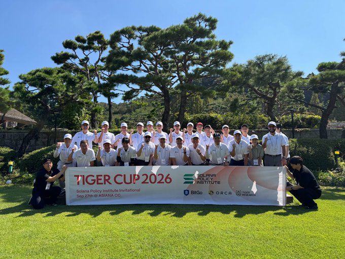 A large group of people pose behind a banner reading 'TIGER CUP 2026, Solana Policy Institute Invitational, Sep 27th @ ASIANA CC' with sponsor logos including Solana Policy Institute, BitGo, ORCA, and Superblock.
