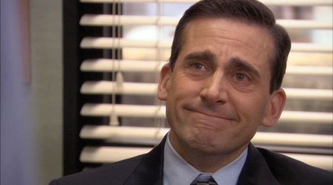 A close-up reaction meme of Steve Carell's character Michael Scott from The Office, displaying an awkward, teary-eyed forced smile.