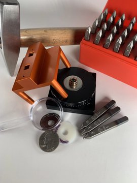 A hammer, orange and red tool cases containing screwdriver bits and wrenches, along with a small washer and screw, are arranged on a surface—illustrating the post's suggestion of "stamping your seed" using a tiny washer and screw to hide valuables in structural elements of a home.