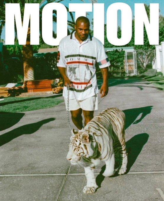 A magazine cover titled 'MOTION' featuring a man in a white Tommy Hilfiger shirt walking a white tiger on a chain down a driveway.