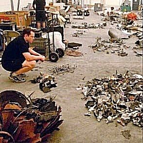 A man crouches in a warehouse surrounded by massive piles of disassembled metal components and debris, inspecting the wreckage. The scene reflects the post's lament about the toll of the "bull run," symbolizing the overwhelming aftermath of a failed venture or obsession that led him to quit his job.
