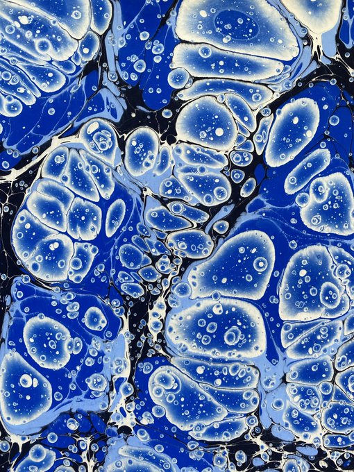 A vibrant blue and white marbling artwork (Ebru) featuring organic, flowing bubble-like patterns against a deep blue background, shared as a "good night" post by artist Battal. The piece exemplifies traditional Turkish marbling art with its swirling, cellular forms and rich blue tones.
