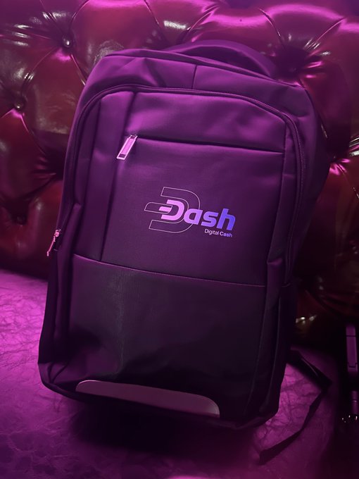 A black backpack with a "Dash Digital Cash" logo, placed against a tufted leather couch illuminated with purple lighting.
