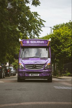 A purple Mercedes-Benz delivery truck with "SOLANA" branding driving down a tree-lined street.