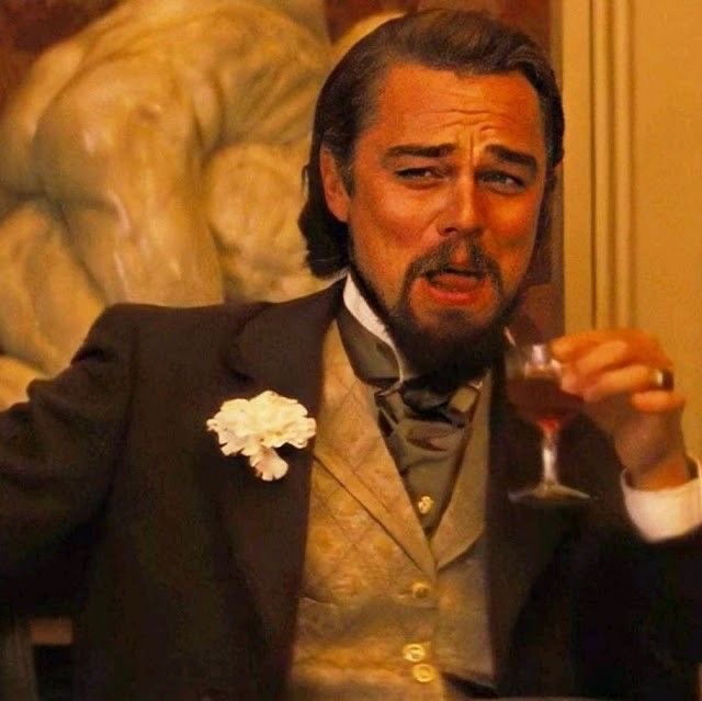 Leonardo DiCaprio, dressed in a period tuxedo and raising a glass of wine with a defeated expression, is shown in a still from Django Unchained. The image humorously conveys the meme's punchline—giving up on betting against Solana after it hit $100.
