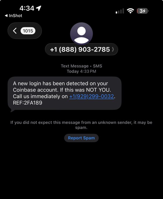 An iPhone screenshot of an SMS message from +1 (888) 903-2785 claiming a new login was detected on a Coinbase account, urging the recipient to call +1(929)299-0032 and referencing REF:2FA189, with a 'Report Spam' option visible.