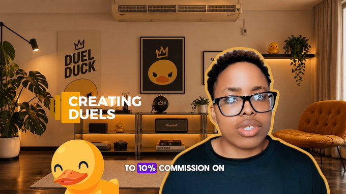 A man with glasses speaking in front of a room with "DUEL DUCK" branding, framed artwork, and a duck figure; text reads "CREATING DUELS TO 10% COMMISSION ON".