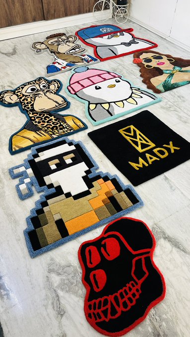 A collection of colorful character rugs and mats displayed on a marble floor, including designs of a leopard, penguin, pixelated characters, a skull with red detailing, and a black rug with the yellow 'MADX' logo.