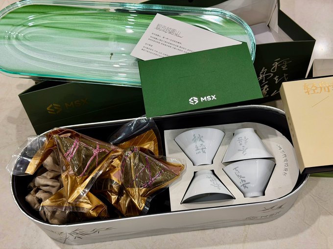 The image features an assortment of items, including a box containing tea cups and a green tray with food wrapped in plastic bags. The boxes are placed next to each other, creating an interesting visual effect. The post about Dragon Boat Festival gifts suggests that these items might be related to the event or could be part of a collection for sale.