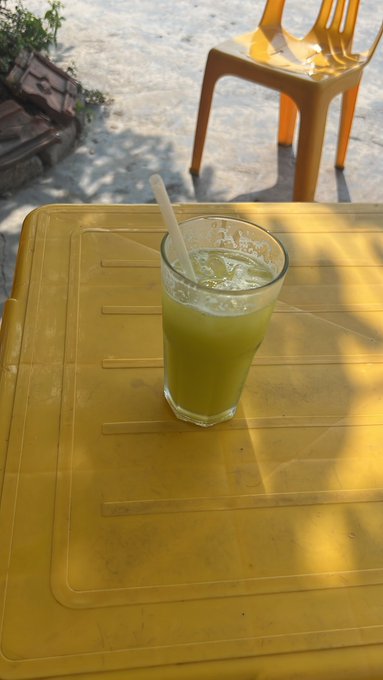 "GM CT Hey guys, are you up yet? Monday, wake up a bit early, everyone Grab a glass of sugarcane juice first @useTria @XOOBNetwork @quipnetwork @TheARCTERMINAL". The image features a yellow table with a tall glass filled with green liquid.