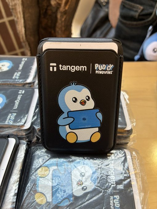 A black leather wallet/cardholder featuring a Tangem x Pudgy Penguins collaboration design with a cartoon penguin holding a blue card.