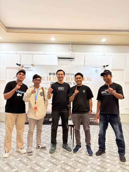 A group of five men pose together indoors in front of a banner that reads 'BYBIT INDONESIA LAUNCHPAD ROADSHOW AND CITY SUMMIT', with some wearing BYBIT Indonesia branded shirts.