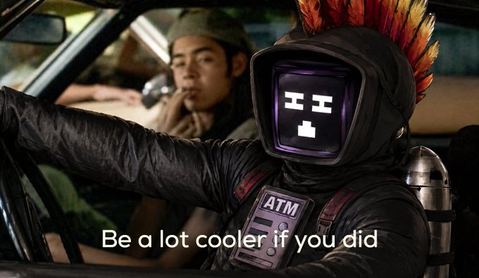 The image features a man dressed as an ATM character with a red feather boa, sitting inside a car. The text "Be a lot cooler if you did" is written above him, which could be interpreted as a motivational message or encouragement for someone who has recently participated in a show or event.