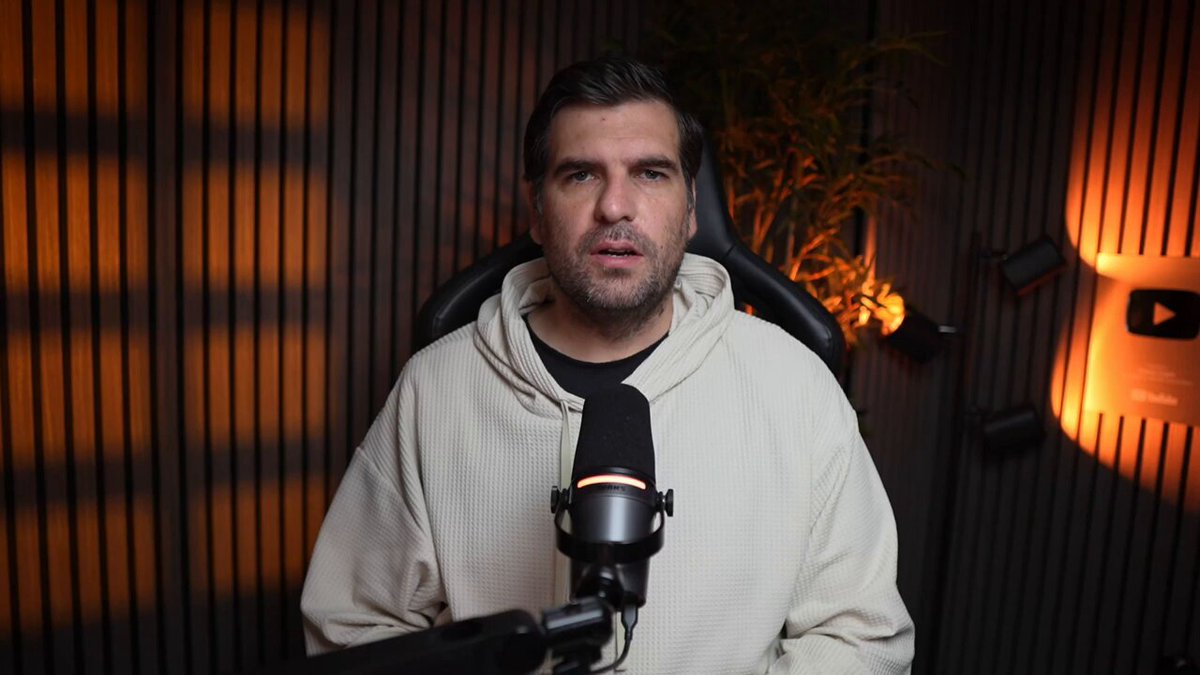 The image shows a man wearing a white hoodie, sitting behind a microphone while speaking into it. The background features a dark wood paneled wall that has a plant placed near it. The caption of the image reads "CARDANO HOLDERS: This 3-year deal changes the ADA utility debate from theory to real-world testing". The post highlights how Cardano's partnership with the Brazilian Olympic Committee is changing the way people perceive and understand the ADA utility debate, as it goes beyond just discussing the topic in a controlled environment.
