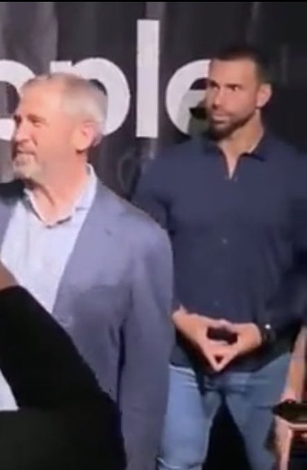 Two men stand at what appears to be a professional event, with one in a gray blazer and the other in a dark blue shirt, with partial text "...ple" visible in the background suggesting a company logo. The image appears to illustrate the post's point about influential, largely unseen figures involved with XRP globally.