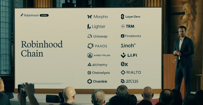 A presentation slide titled 'Robinhood Chain' listing partner companies including Morpho, Layer Zero, Lighter, TRM, Uniswap, Fireblocks, Paxos, 1inch, Arbitrum, LI.FI, alchemy, 0x, Chainalysis, RIALTO, Chainlink, and arcus, with a speaker on stage.