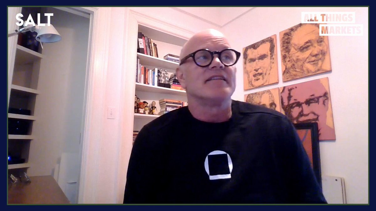 The image shows an older man wearing glasses, sitting at a desk with a computer screen in front of him. The background features several framed pictures hanging on the wall above his head. The text displayed on the screen reads "Bitcoin is bleeding; the most important IPO moment in market history, with SpaceX, Anthropic, and OpenAI all heading to public markets simultaneously; why the data center buildout is falling dangerously behind schedule".