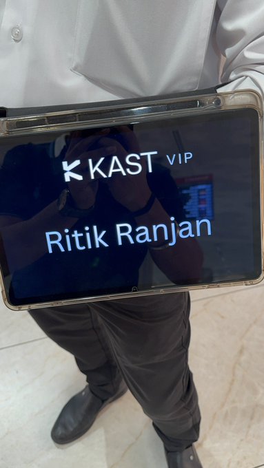 A person holding a tablet displaying "K KAST VIP" with the name "Ritik Ranjan" in white text on a dark background.