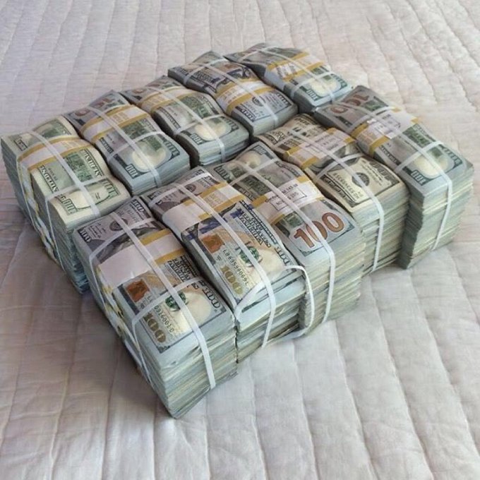 Multiple stacks of US $100 bills bundled together with currency straps, arranged in a grid on a light-colored surface.