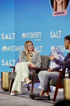 A woman and a man sit in chairs on stage at the SALT Conference, set against a backdrop featuring "SALT" and "kraken" logos, with a "MODERATOR" label visible at the top of the frame. The image captures the panel discussion mentioned in the post, where the moderator interviewed Arjun Sethi, co-CEO of Kraken, about Payward's vision for an open financial system.