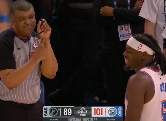 The image shows a basketball game with two players, one wearing an Oklahoma City Thunder jersey and the other wearing a referee's uniform. They are both smiling at each other while standing near the center of the court. The referee appears to be giving a thumbs up or a high five gesture towards the player in the Thunder jersey.