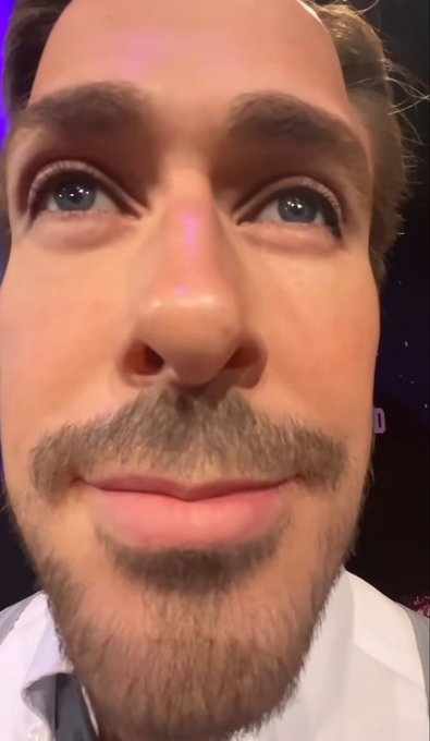 Close-up selfie of a man with brown hair, a mustache, and a beard, wearing a white shirt.