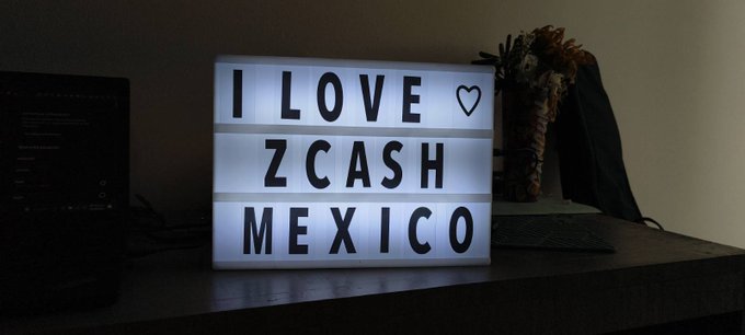 A lightbox sign displays 'I LOVE ♥ ZCASH MEXICO' on a desk next to a laptop and decorative vase.