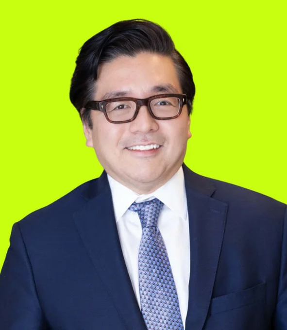 A portrait of a smiling Korean man wearing glasses, a dark navy suit, white shirt, and patterned blue tie against a bright lime green background.