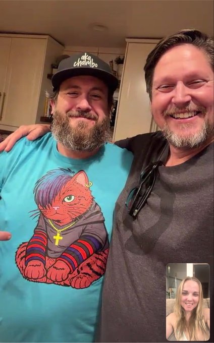 The post is about web3 creators connecting in real life, and the image shows two smiling men posing together, one wearing a teal t-shirt featuring a Chucky-style cat graphic and a black baseball cap with "chambo" written on it, while the other wears a gray shirt with sunglasses tucked into the collar. The smaller inset video call window in the bottom right corner shows a blonde woman who appears to be joining the interaction remotely.