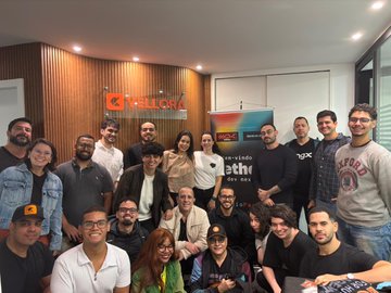 The image features a group of people posing for a photo, likely at a company event or gathering. The individuals are standing close together, with some members positioned behind others. They appear to be employees from a company named "Tether Dev Nexus". In the background, there is an advertisement for a streaming service called "WDK" and another advertisement for a payment processing service called "MDK". The group seems to be enjoying themselves as they pose for the picture together.