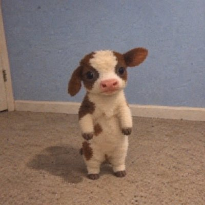 A small brown and white calf plush toy standing upright on its hind legs on a beige carpet against a blue wall.