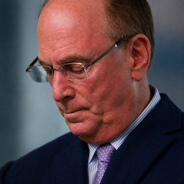 A close-up photo shows a man with short gray hair, wearing rimless glasses, a dark navy suit, and a purple patterned tie, looking downward with a serious expression. The image appears to be of a financial industry figure, likely relating to the news of major ETF providers like BlackRock and Fidelity selling $144.6 million worth of Bitcoin.