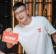A smiling young man wearing glasses and a white Tesla t-shirt holds up a red card reading "50 USDT".