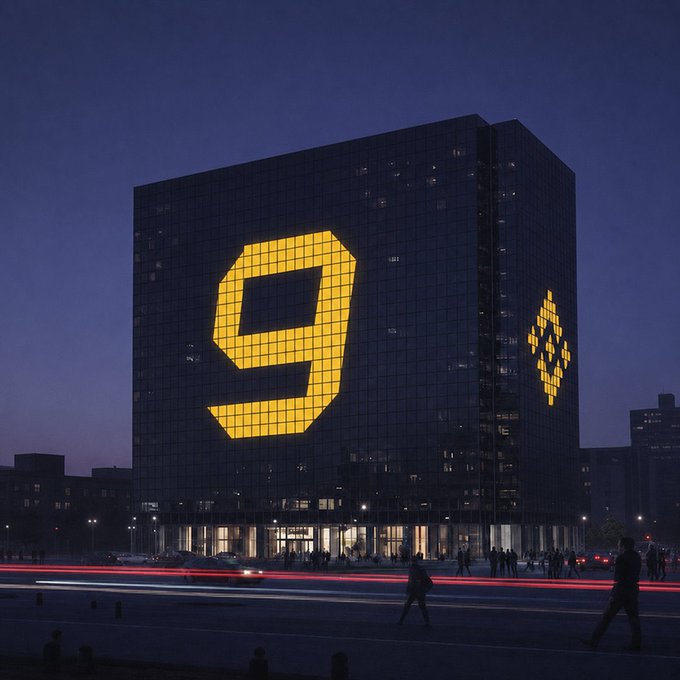 A nighttime cityscape showing a modern building with a large illuminated golden '9' and the Binance logo lit up on its facade.
