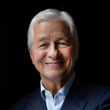 A professional headshot of a smiling older man with silver hair wearing a dark suit against a black background, likely a stock photo used to illustrate the post about JPMorgan's bullish Bitcoin commentary on Strategy's $3B cash reserve.