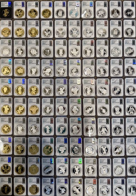 A large collection of graded coins, mostly silver, displayed in plastic slabs arranged in a grid pattern.