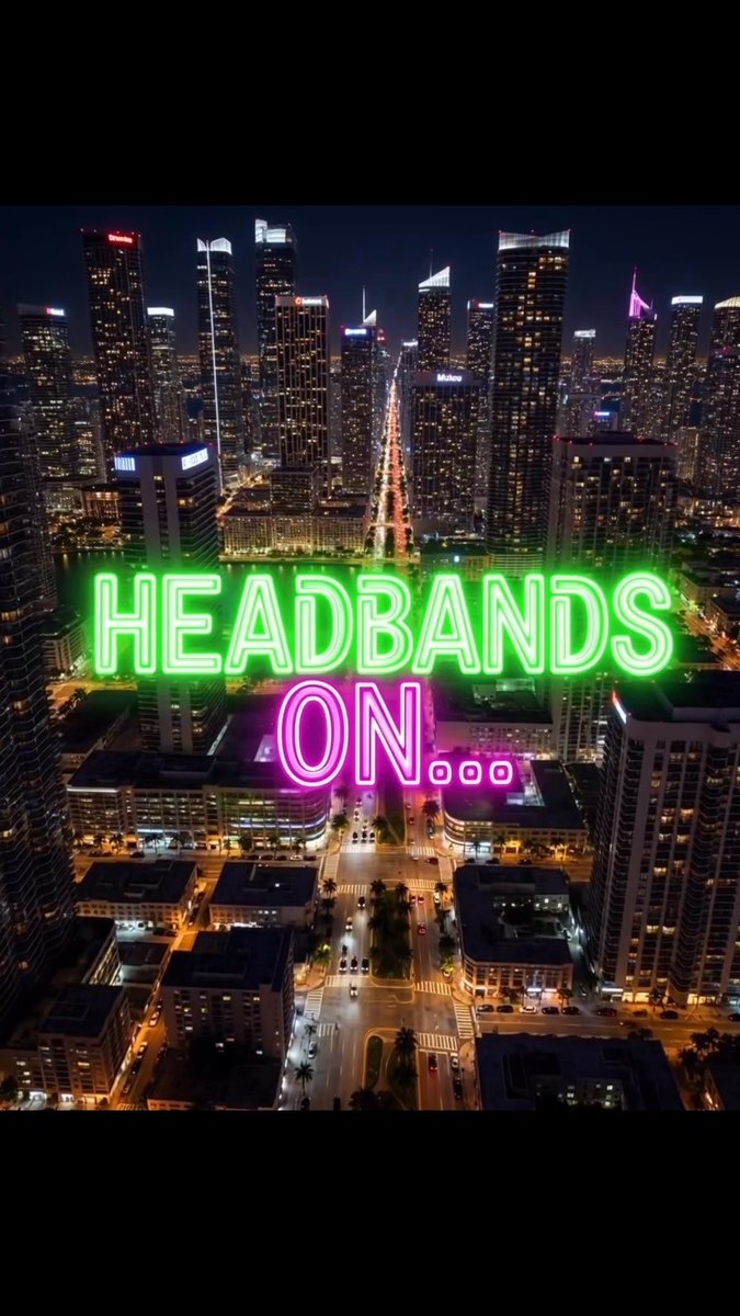 A nighttime aerial view of a brightly lit city skyline with the glowing neon text 'HEADBANDS ON...' overlaid on the center.