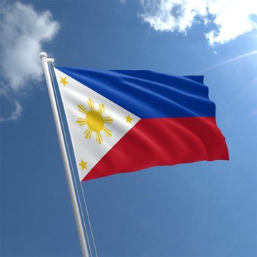 The image features a flag flying high against a blue sky with white clouds, which appears to be the Philippine flag. The flag has red, white, and blue colors, along with yellow stars that represent the sun. There are also some words written on the flag, but they are not clear enough for me to determine their exact meaning or significance.