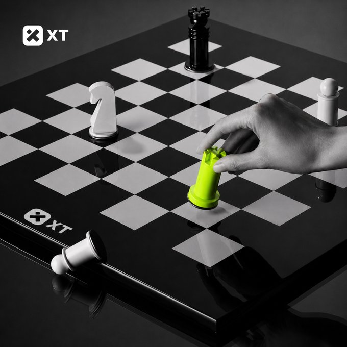 A hand places a green chess rook on a black-and-white board alongside a knight, king, pawn, and fallen pieces, with the "XT" logo appearing in the top-left and on the board itself. The chess imagery visually echoes the caption's message about making the right strategic move, reinforcing the post's call to trade confidently on XT.