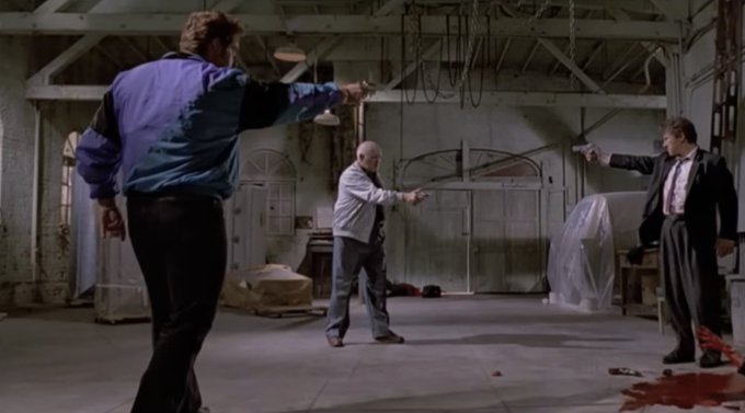 Three men in a dim warehouse point guns at each other across the room, with a bloodstain visible on the floor, humorously illustrating the post's point that protecting your bitcoin requires serious self-custody—no one else will truly keep it safe for you.
