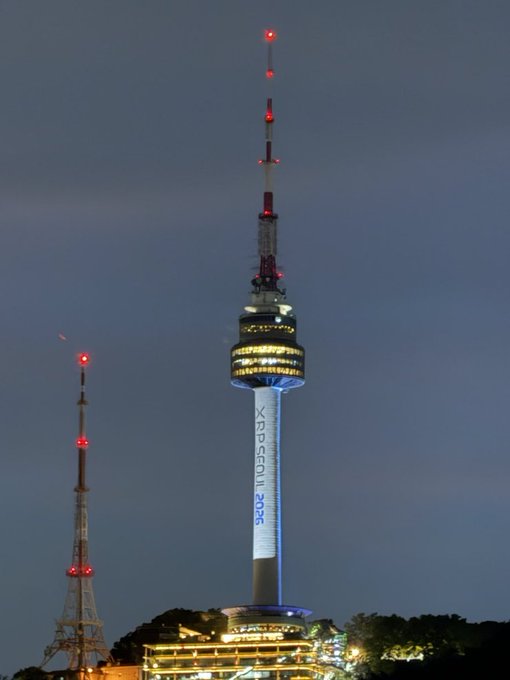 A twilight photograph of N Seoul Tower lit up with 'XRP SEOUL 2025' displayed on its facade.