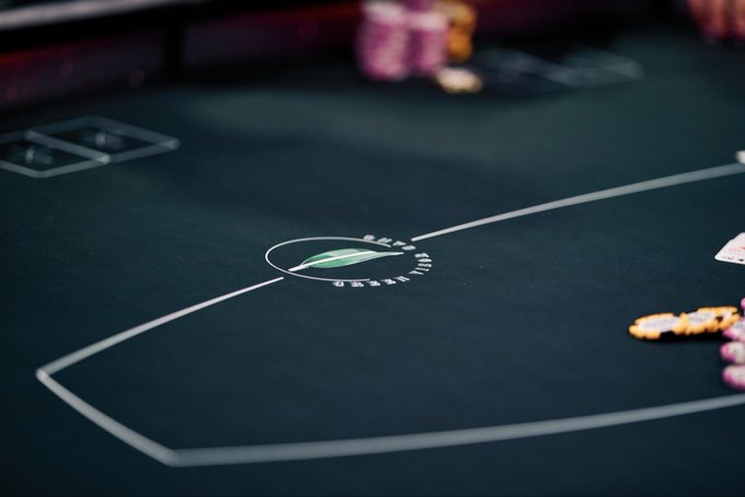A close-up shot of a poker table featuring the Beau Rivage casino logo, showing chips and playing cards on the green felt surface.