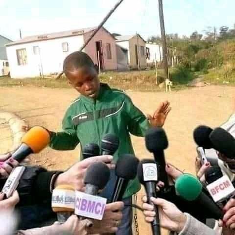 A man in a green jacket stands outdoors speaking to a cluster of microphones from outlets like BMC and BFCM.