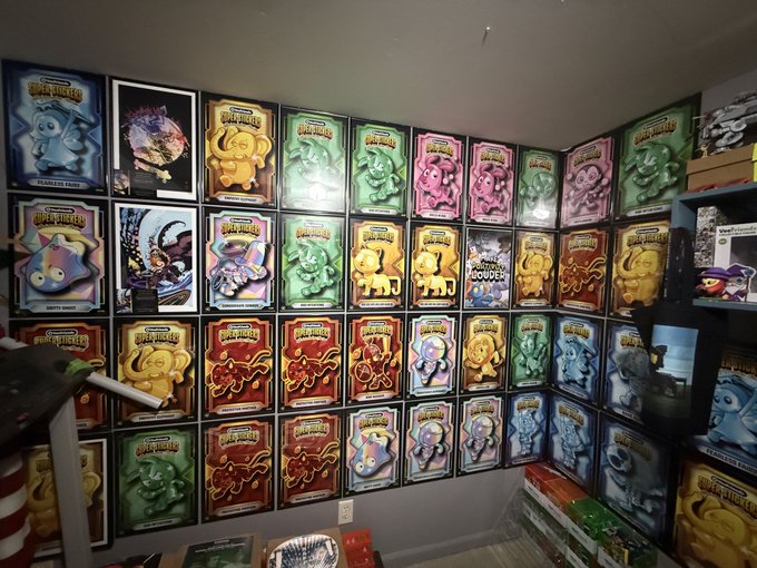 A room corner wall covered with a large collection of framed prints featuring various colorful, cartoonish character designs.
