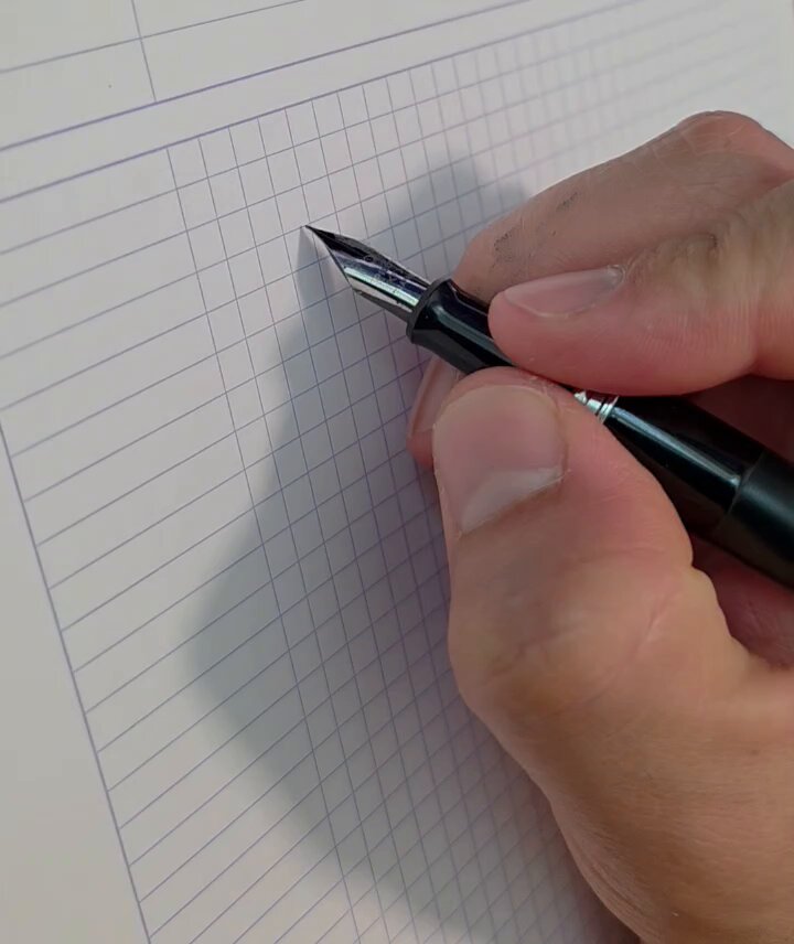The image shows a hand holding a fountain pen over a sheet of lined paper, with the pen's nib pointing towards the top left corner of the page. The text "It feels like a fountain pen day. Let' s do something fun; $100 in ETH to the first person to comment what I've written here." is visible on the image.