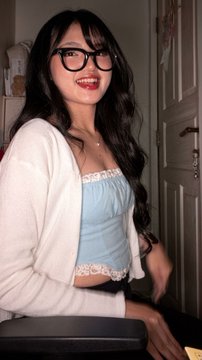 A smiling young woman with long dark hair and glasses poses wearing a light blue lace-trimmed top under a white cardigan. The caption "Nice cenblu" appears to be a playful compliment referencing her blue outfit.