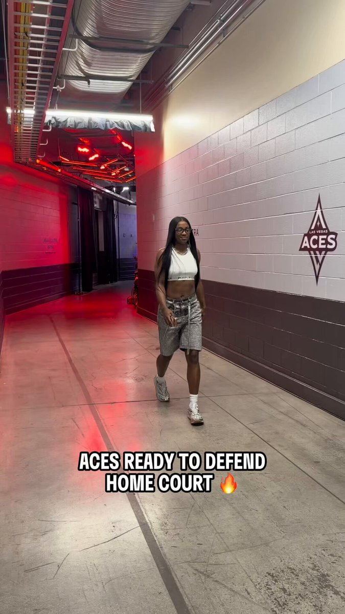 The image shows a woman walking down an empty hallway with red lights above her, possibly indicating that she is entering or leaving a game room. The caption of the image reads "Aces Ready to defend home court", which suggests that they are preparing for a basketball game at their home court.
